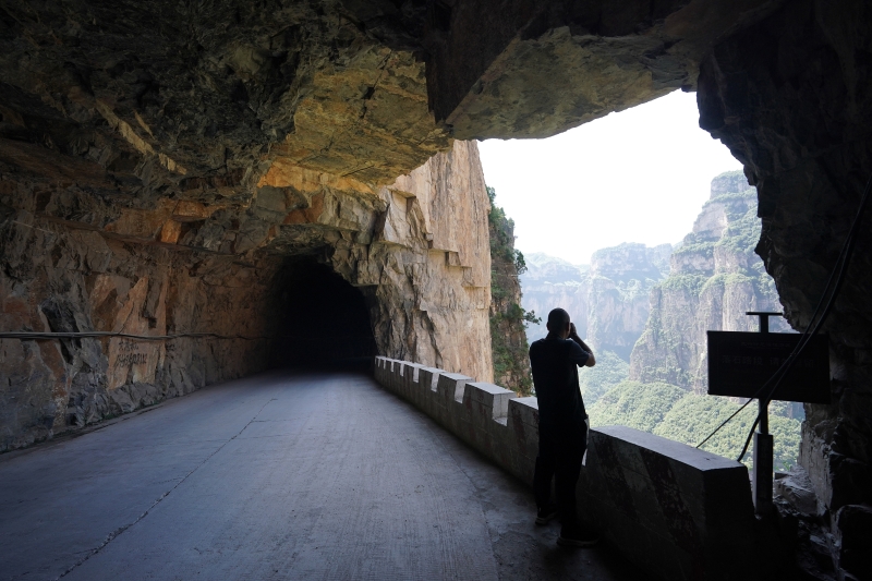 一名游客在山西省平顺县“太行天路”上驻足拍摄大峡谷风景。