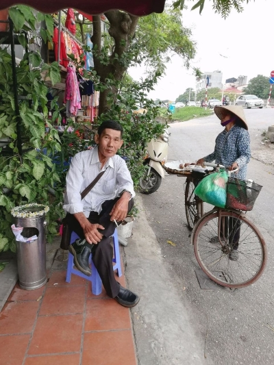 坐在餐馆外头休息的父亲，和推着脚车叫卖的越南妇女相映成趣。

