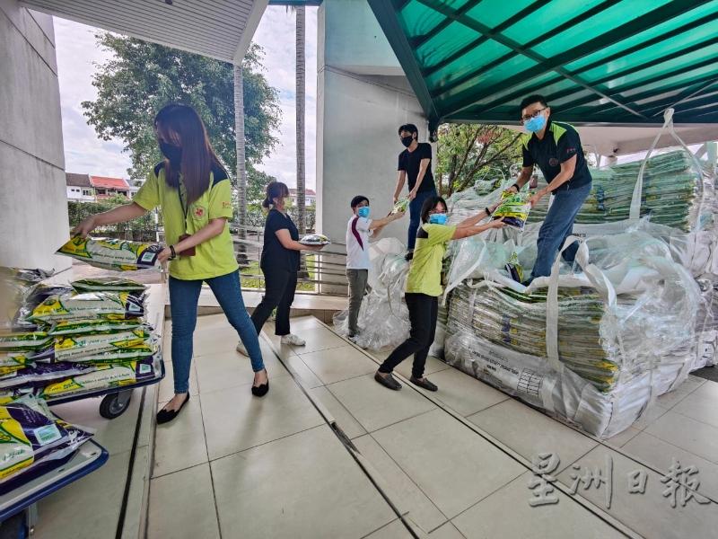 星洲日报的员工在合力将米粮搬下来，以分配给各地办事处。