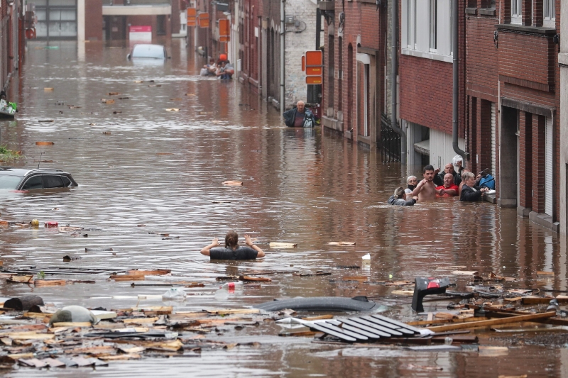 比利时列日市大雨过后，一名妇女正试图在洪水淹没的街道上救出其他人。