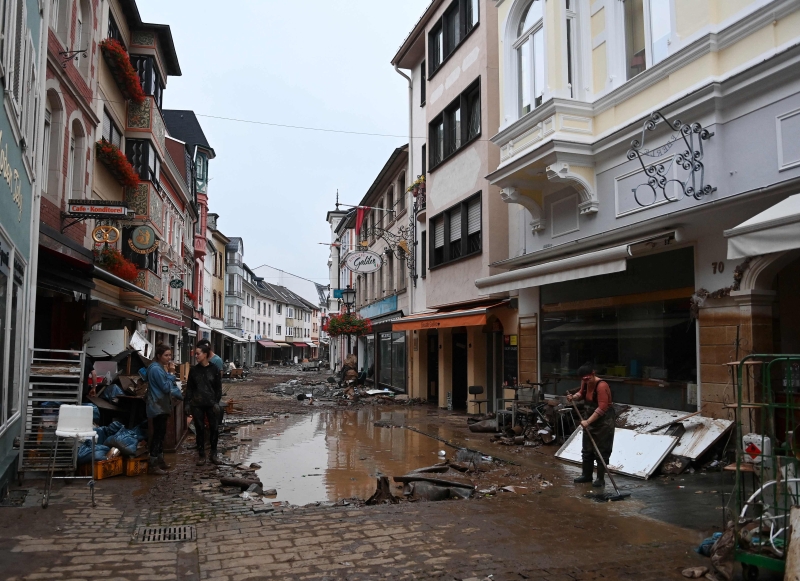 德国西部 Ahrweiler-Bad Neuenahr商业区洪水冲击后，一名居民正在清理街道。