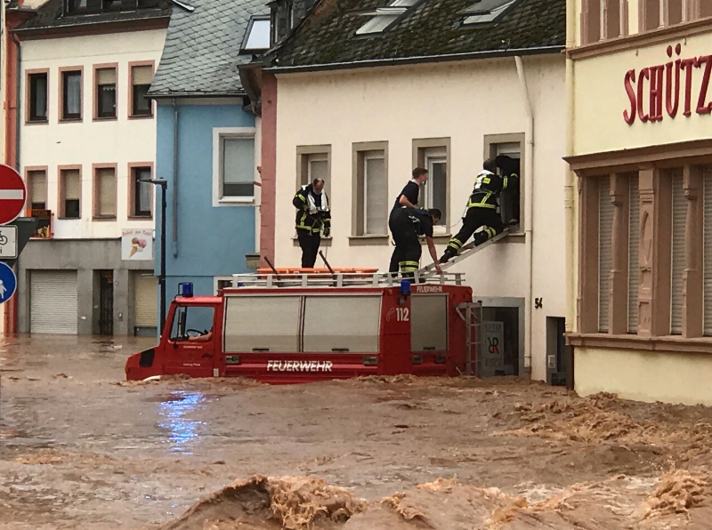 德国西部特里尔被洪水淹没，消拯员从车顶上的爬进屋内救援。