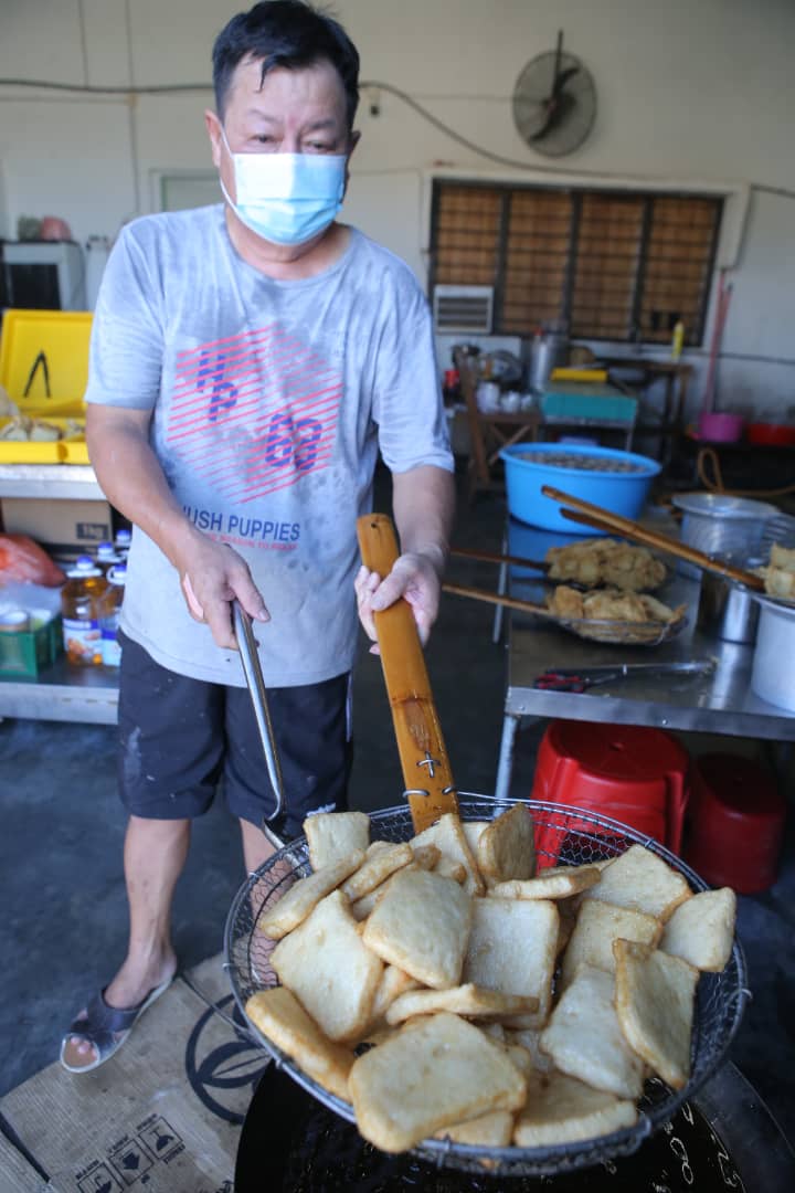 锺海城把已经切片的鱼饼放入油锅中油炸。