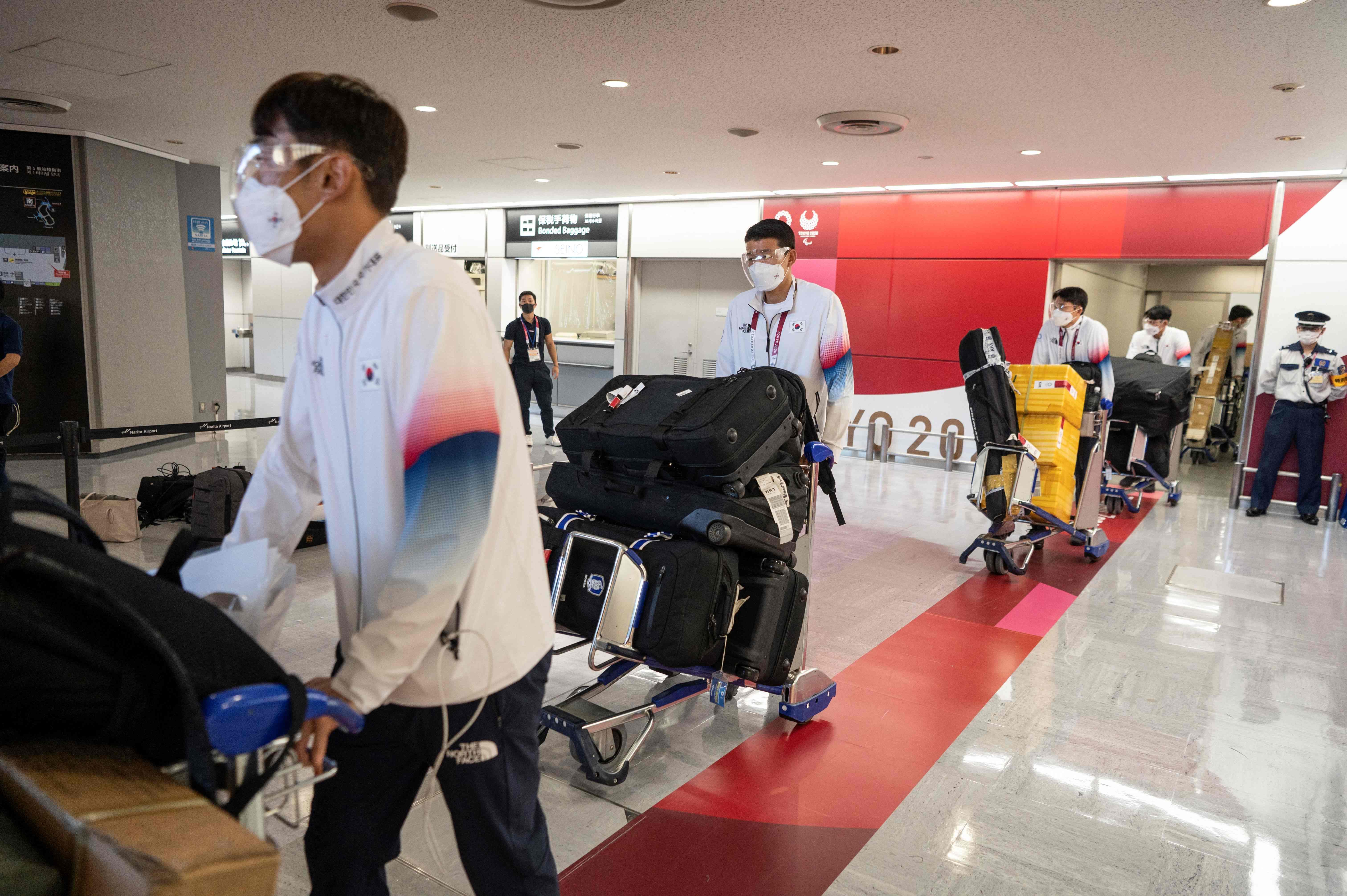 韩国前奥运冠军柳承敏抵达日本后无症状确诊，正接受隔离。图为韩国男足队员抵达成田国际机场。（法新社照片）

