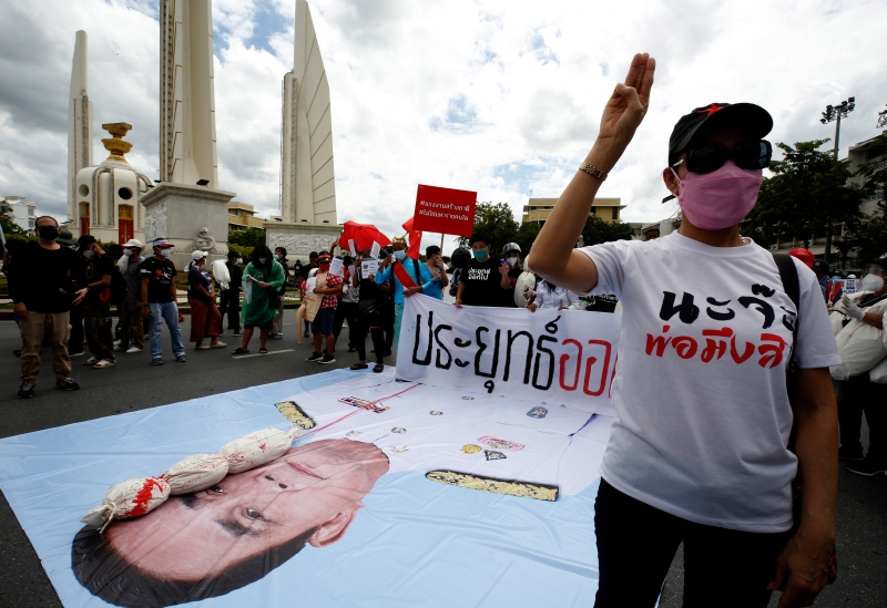 三指手势已然成为示威民众的象征，一名与会者在泰国首相巴育的大型肖像前高举该手势。（欧新社图片）