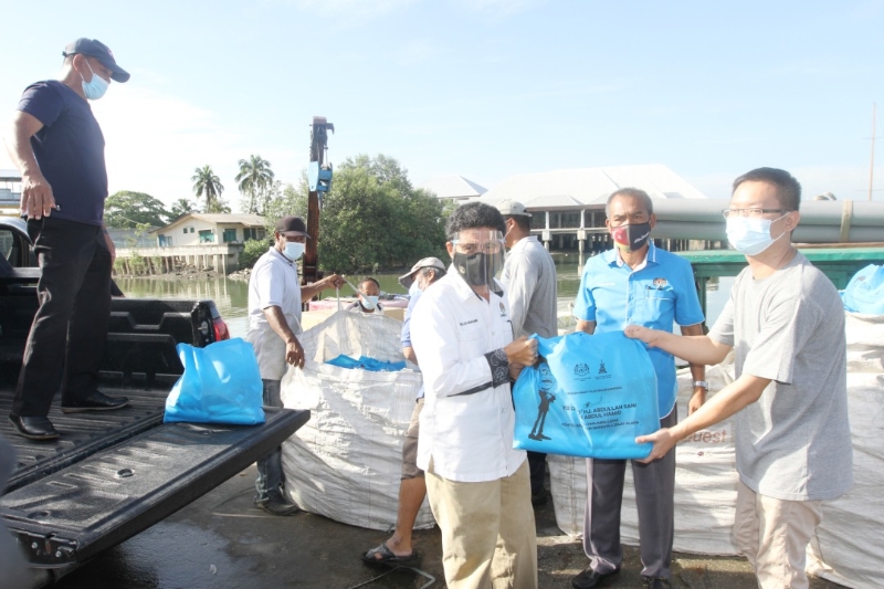 加埔国会议员阿都拉沙尼（左）移交各50袋食物篮给吉胆岛和五条港，以捐赠给岛上的贫困家庭。右一为吉胆岛村管委会秘书蔡明爵。
