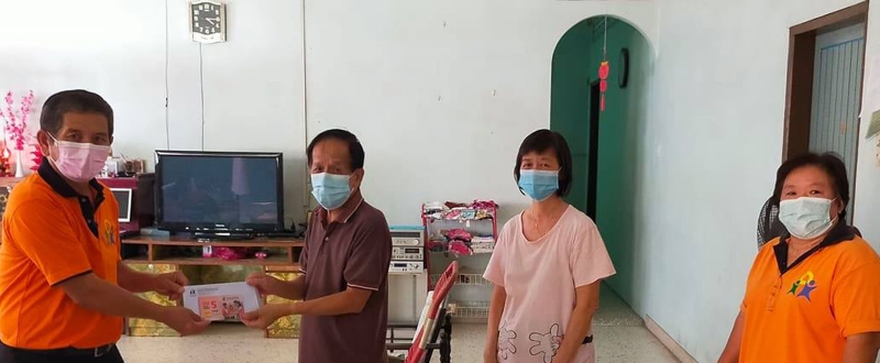 曼绒新希望关怀机构副主席瞿述连（左）移交购物券给其中一户失业家庭；右一为义工彭桂珠。