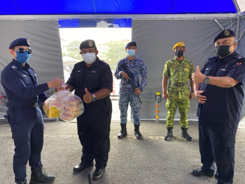 阿末礼万（左）派发哈芝节食品饮料给在路障处执勤的军警人员。右为副警区主任卡玛阿里芬副警监。