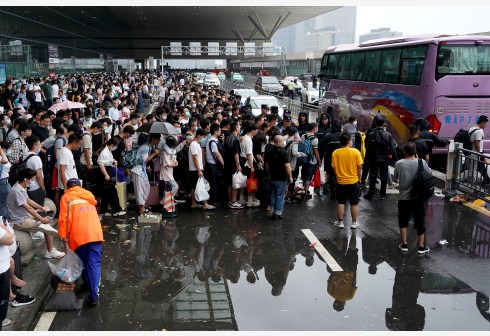 滞留旅客在郑州东站进站口处排队登乘大巴车。