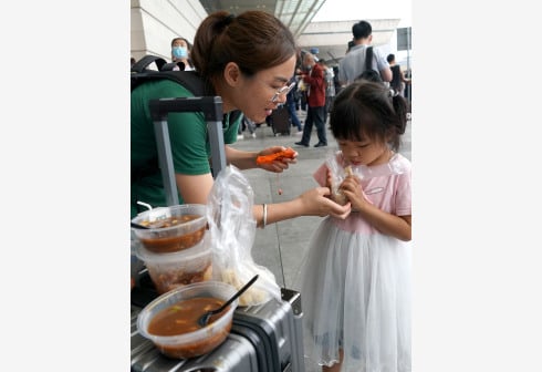 一名滞留旅客在郑州东站进站口处喂孩子吃早餐。