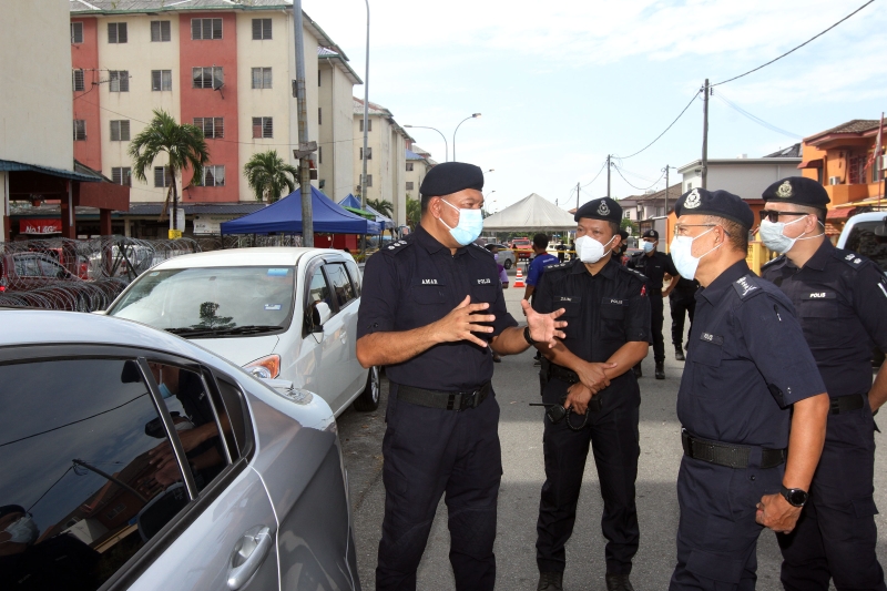 三苏阿马（左一）向阿尊奈迪（右二）汇报警方在组屋封锁区的工作情况。