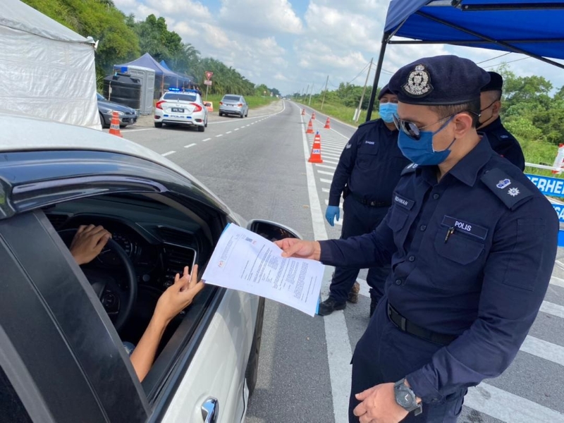 阿末礼万警监（右）在一个路障处检查途经车辆通行证。