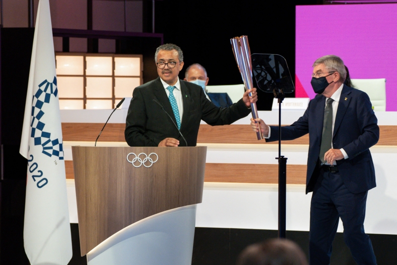 世界卫生组织总干事谭德塞（左）周四在东京从国际奥委会会长巴赫手中接过东京澳运会火炬。（图：法新社）