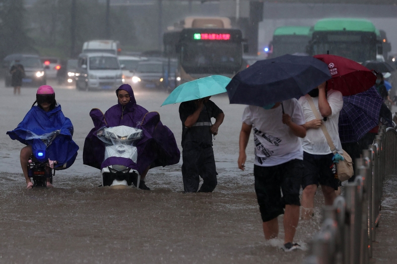 郑州连日大雨后，许多街道发生水浸，市民只能冒险涉水越过。（法新社照片）