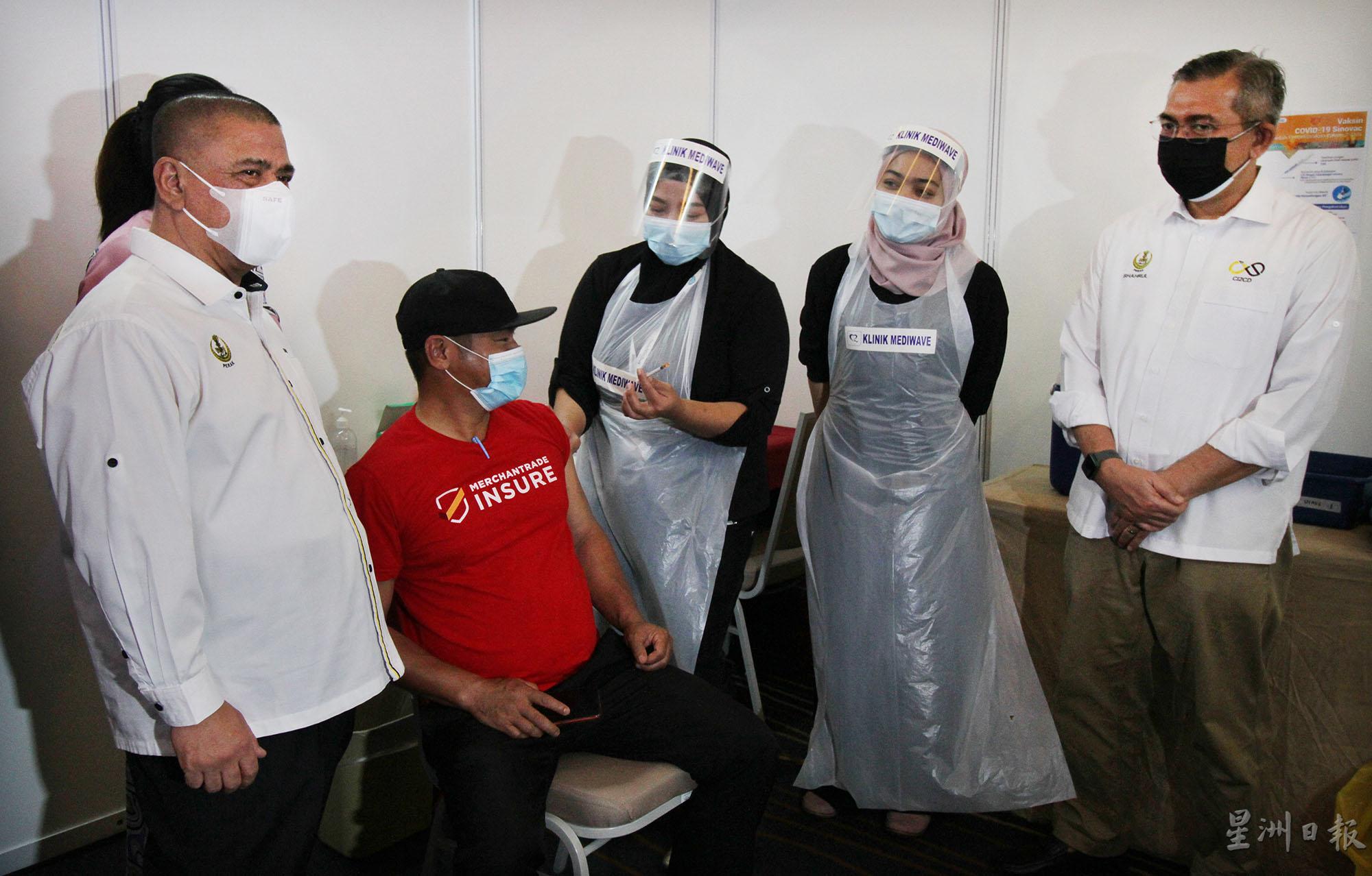 沙拉尼（左一）巡视医护人员为制造业员工接种疫苗的情况。右一是沙鲁沙曼。