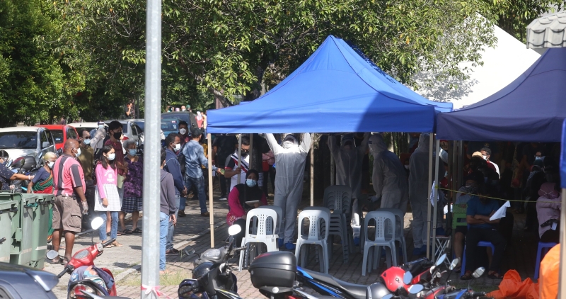 工作人员穿上防护衣设立帐篷及排椅子，让前往冠病评估中心的民众无需在太阳下暴晒。