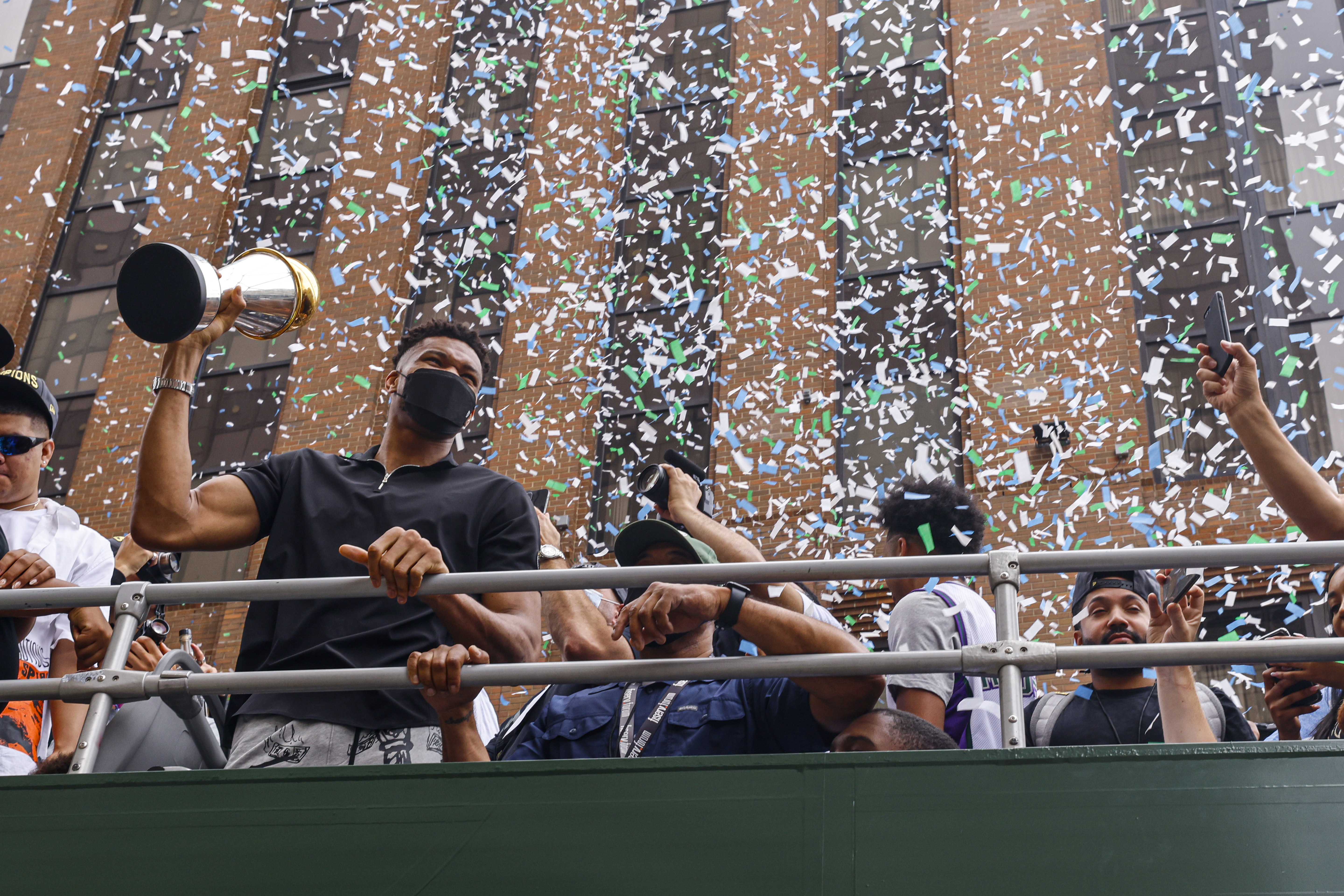 “字母哥”安特托孔波（左）在公鹿队NBA冠军游行中，高举决赛MVP奖杯与球迷欢庆。（美联社照片）


