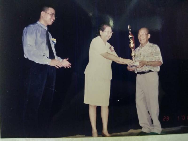陈锡泉受拿汀佘智瑞颁发书法比赛奖杯，旁为筹委会主席薛君毅。
