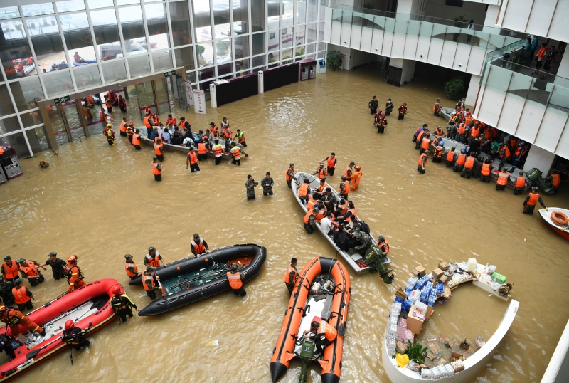 郑州市中牟县阜外华中心血管病医院门诊部，救援人员在积水的大厅内驾驶舟艇转移病患。