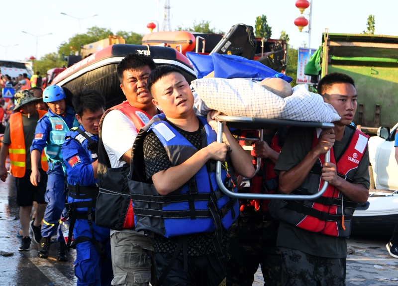 数名救援人员连担架带人一起扛起来，将他移至安全地区。