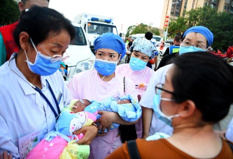 医护人员在检查新生儿状态，准备登上救护车。