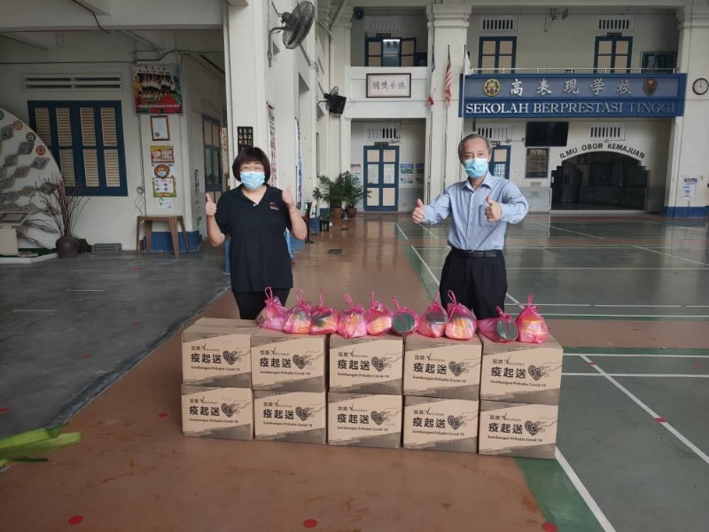 本报业务促进执行员廖凯盈（左一）移交物资予育民小学校长郑国华。