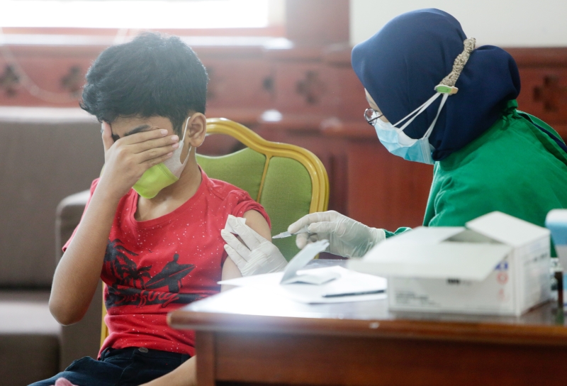 在印尼首都雅加达，一名学生接种疫苗时害怕到遮眼。印尼当局加速为12至18岁的青少年接种，同时也决定将紧急社区活动 (PPKM) 的限制延长至8月2日。（欧新社照片）