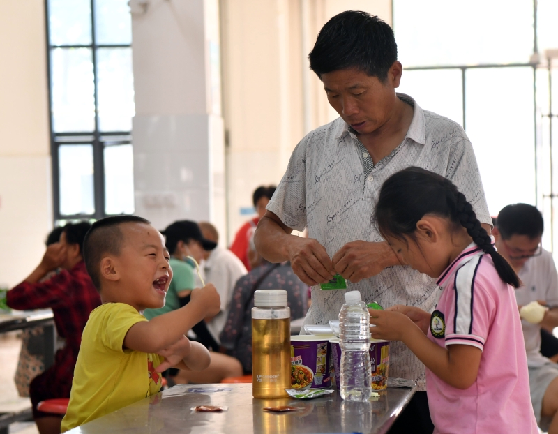 7月24日，群众在淇县职业中等专业学校安置点内准备吃饭。

