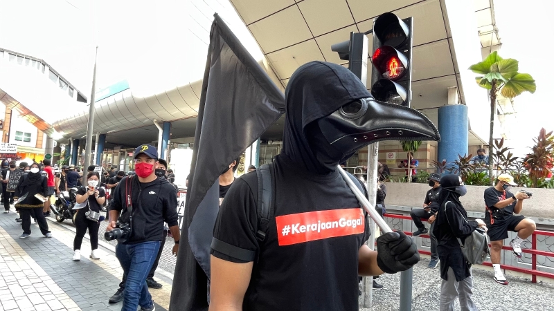 一名举着黑旗，头戴乌鸦面具独特造型的集会者一到现场就成为众人目光。