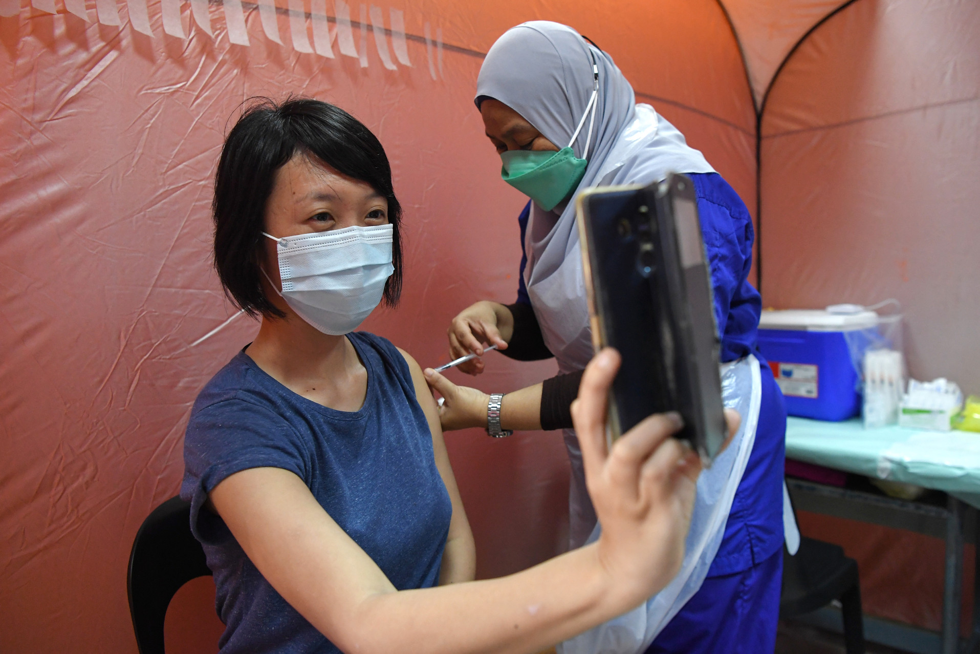 一名业者龙世玲（译音）用手机拍下接种疫苗过程。