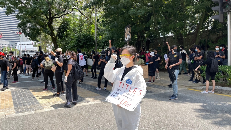 一名集会者身穿防护衣，戴口罩，眼罩，手套做足防疫措施参与抗议游行。