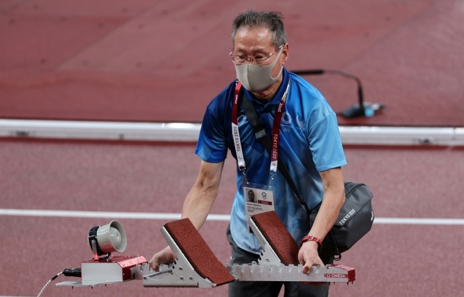 A volunteer sets up a starting block during the athletics at Tokyo 2020. AFP A volunteer sets up a starting block during the athletics at Tokyo 2020. AFP
