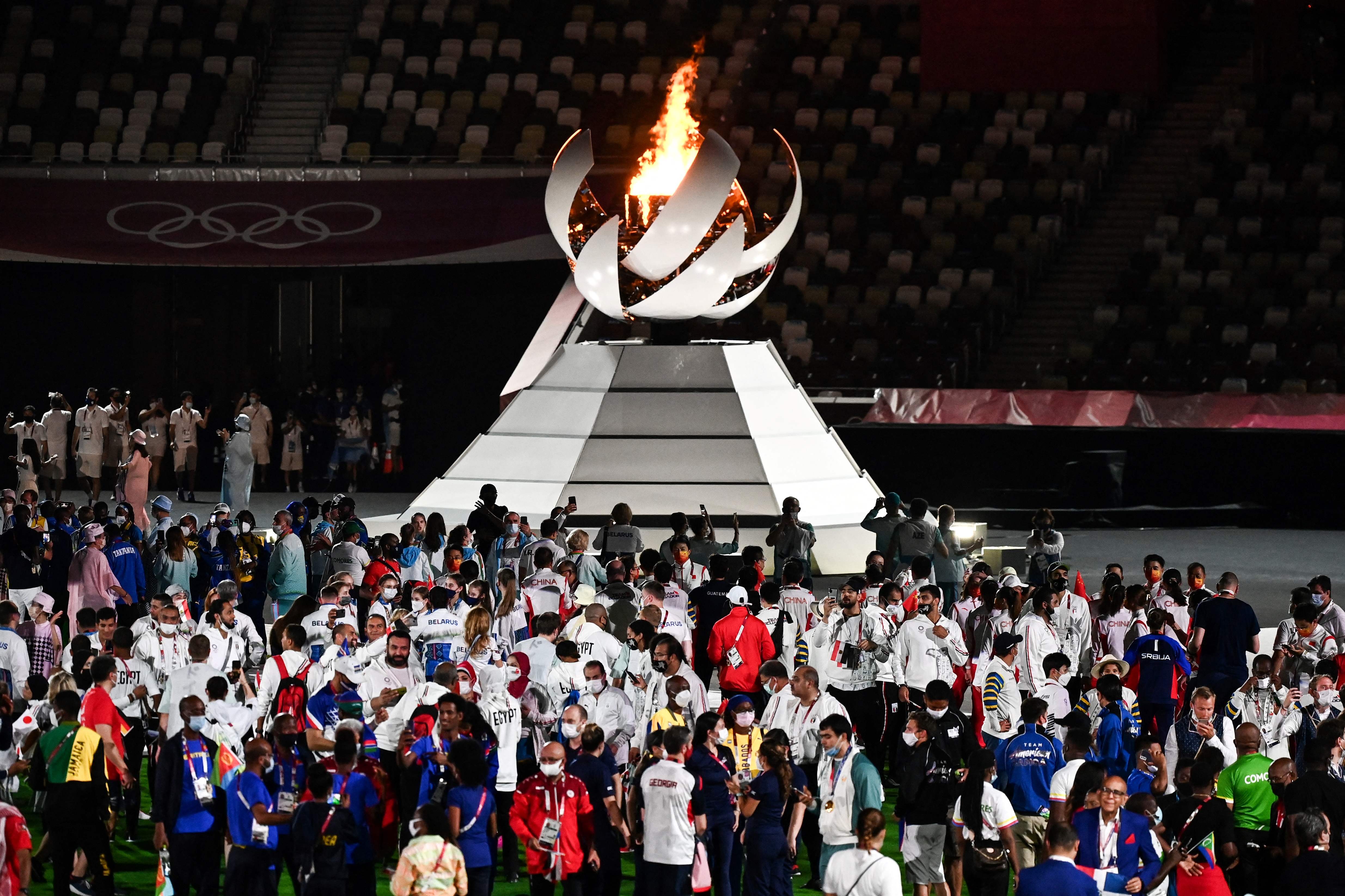在闭幕式上，各国运动员们聚集在奥运圣火旁，庆祝东京奥运圆满结束。（法新社照片）


