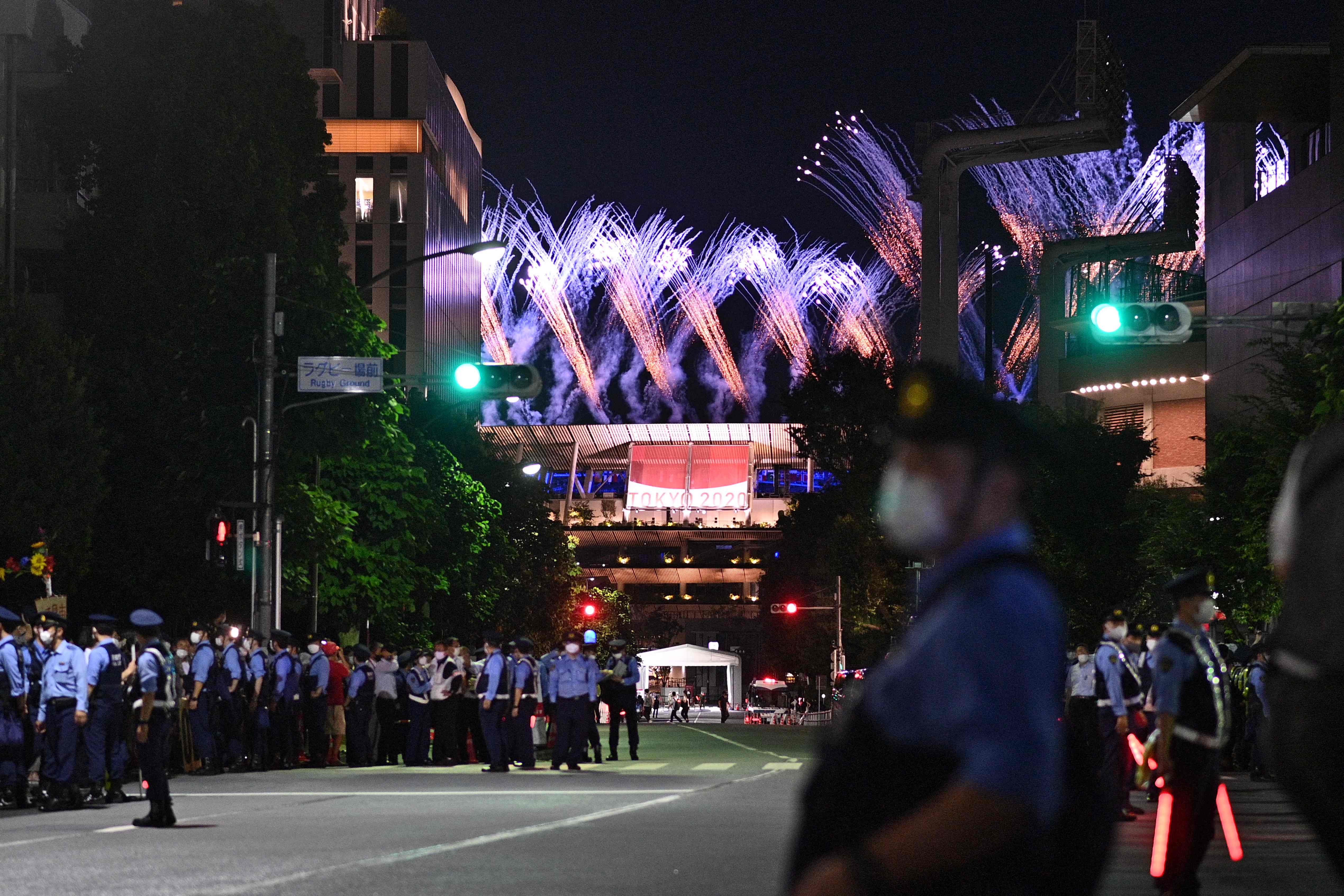 东京奥运会闭幕式期间，五彩缤纷的烟花照亮了奥林匹克体育场的夜空，图为警方在场外维持秩序。（法新社照片）

