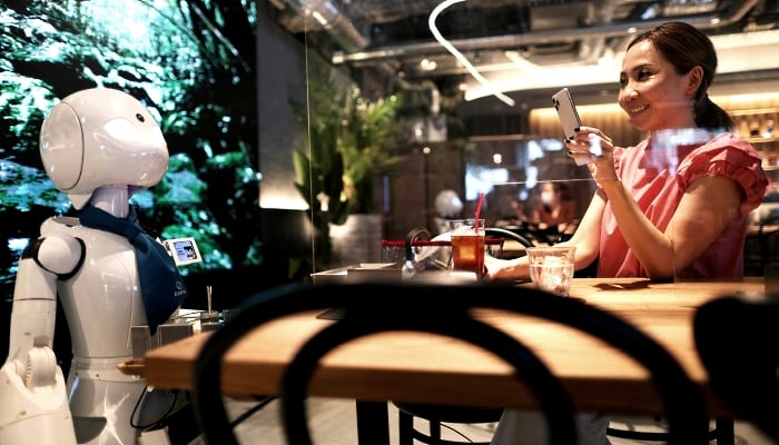 A customer takes pictures of a humanoid robot delivering drinks at the Dawn Cafe in Tokyo. AFP