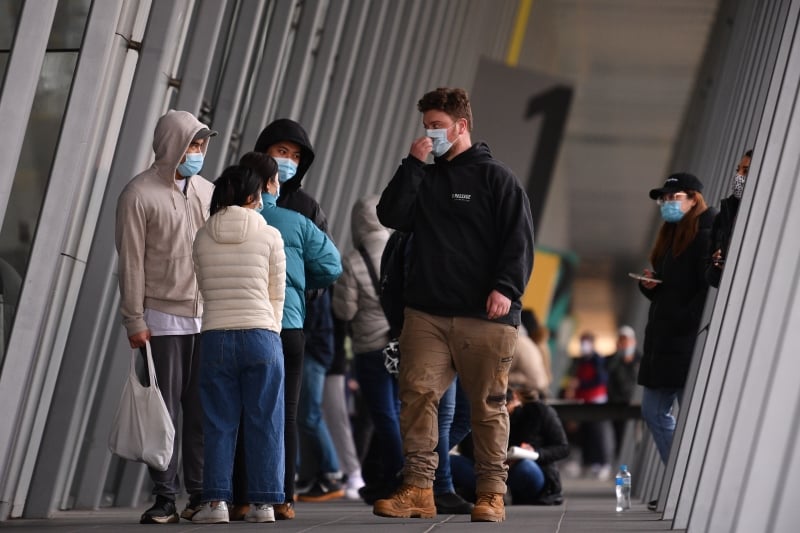 在墨尔本一疫苗接种中心外，戴著口罩的民众排队等候接种。（欧新社照片）